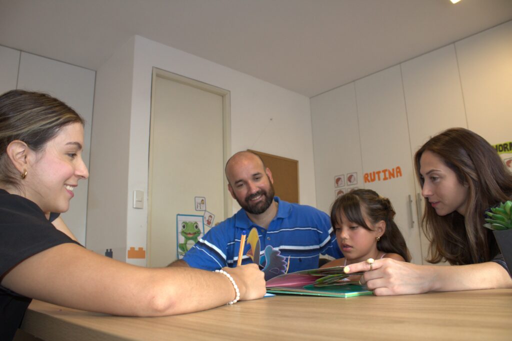 Psicóloga infantil trabajando con una niña y sus padres con material lúdico durante una sesión en LegoMente.