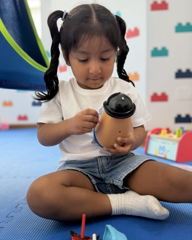 Niña jugando con un muñeco didáctico para practicar habilidades de motricidad fina en LegoMente.