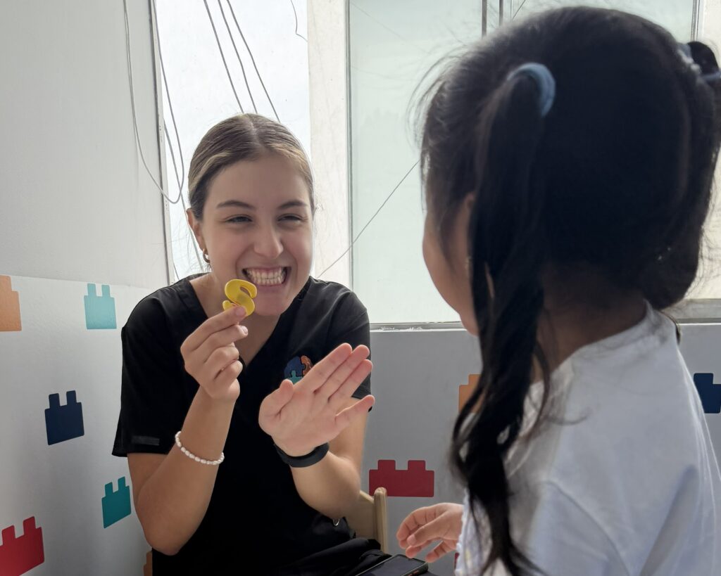 Terapeuta infantil reforzando una actividad de lenguaje con una niña usando letras didácticas en LegoMente.