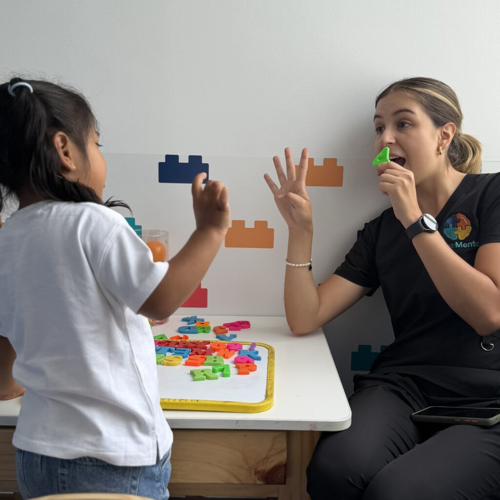 Terapeuta infantil y niña practicando imitación y comunicación con juego de números y turnos en LegoMente.