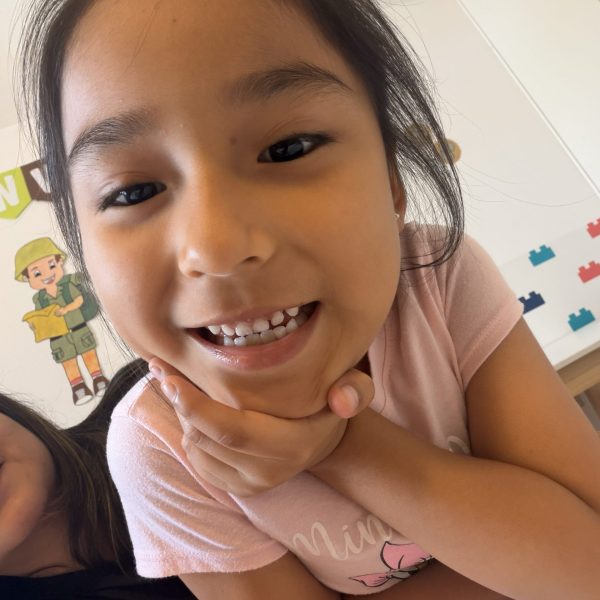 Niña pequeña sonriendo a cámara durante actividad lúdica en espacio terapéutico infantil